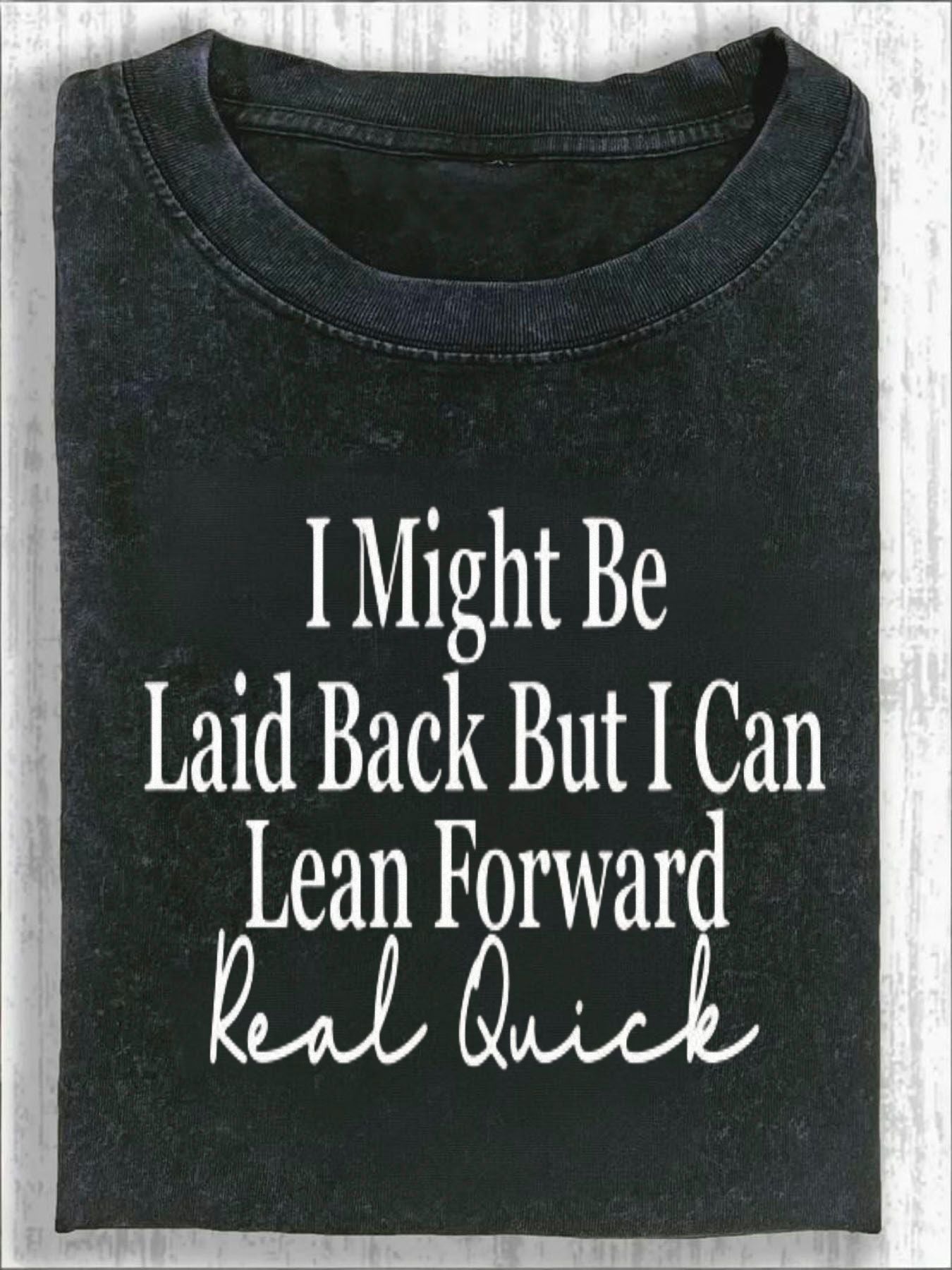 Unisex Crew Neck T-shirt, with Bold Cursive Prints Of White Text On The Front: "I Might, " "Leisurely But I Can, " "Lean Forward Quickly, " And "Really Fast." Fashionable And Casual T-shirt Against A Light Wood Grain Background.