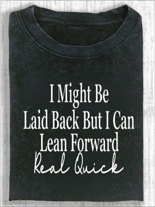 Unisex Crew Neck T-shirt, with Bold Cursive Prints Of White Text On The Front: "I Might, " "Leisurely But I Can, " "Lean Forward Quickly, " And "Really Fast." Fashionable And Casual T-shirt Against A Light Wood Grain Background.